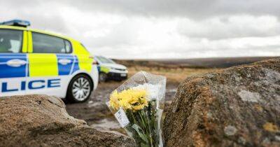 A woman hands an officer flowers in poignant tribute as the police search continues for Moors Murders victim Keith Bennett