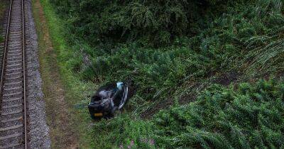 Car crashes near railway line after rolling down embankment