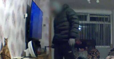 Chilling footage shows masked knifeman creep around living room while homeowner sleeps on sofa behind him