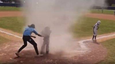 Teen umpire saves 7-year-old from a dust devil swirling near home plate