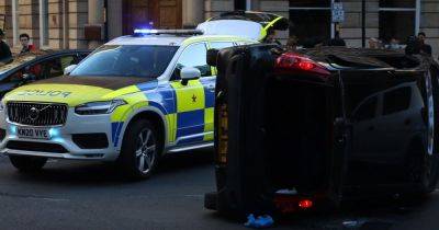 Dramatic pictures as car flips onto side in Manchester city centre as witnesses watch on