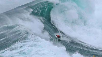 Surfing-Surfers take on giant waves in Nazare as extreme weather hits Europe