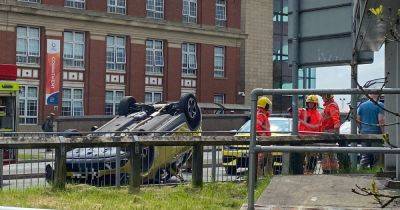 Dramatic moment car is flipped onto roof after being 'smashed into safety barrier' outside college - manchestereveningnews.co.uk