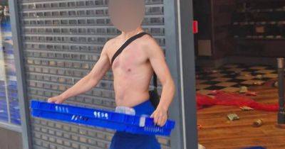 Moment brazen topless looter waltzes out of Greggs with entire tray of food during riots