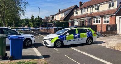 Police tape off street outside house with forensic officers amid fire investigation